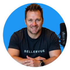 A smiling man with short brown hair sits at a table, wearing a black SELLERVUE T-shirt, with a black microphone on his right, against a solid blue background.