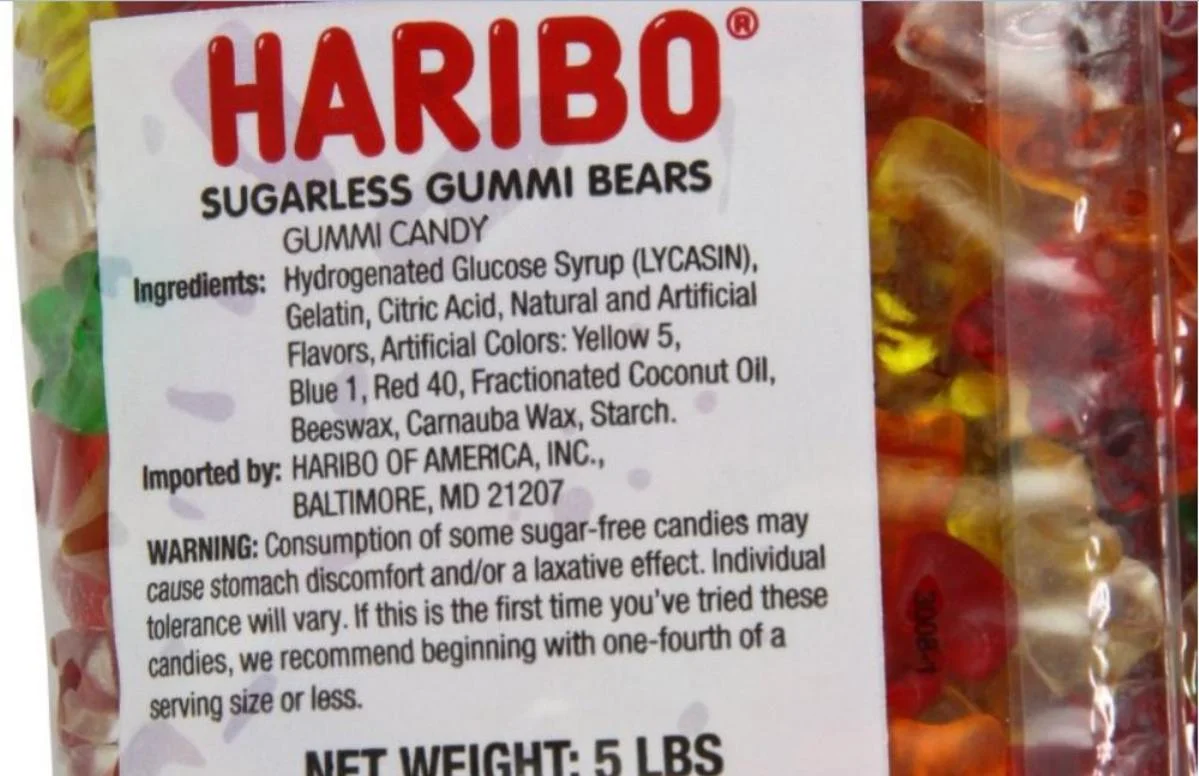 Close-up of a bag of haribo sugarless gummi bears, showing ingredients, warning about possible laxative effects, and a net weight of 5 lbs. Colorful gummy bears are visible through the packaging.